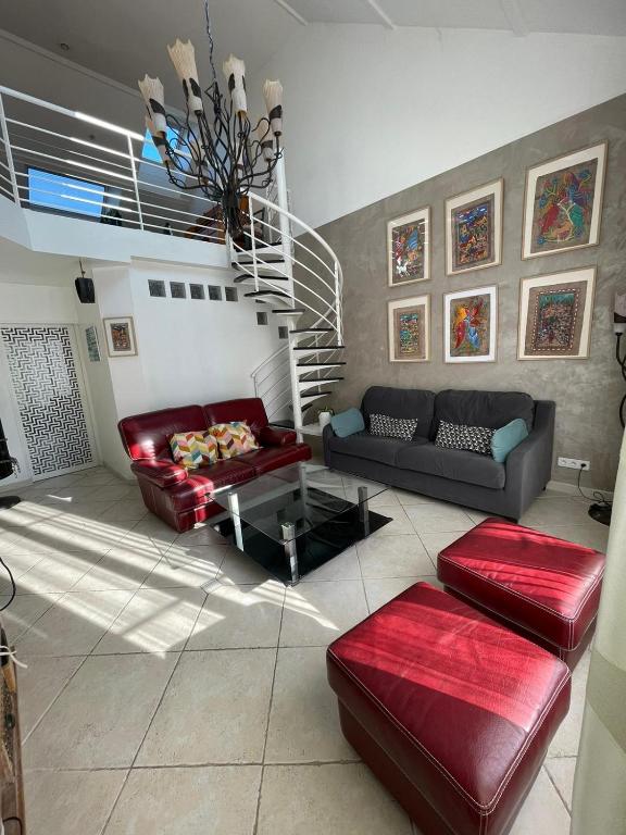 a living room with red leather furniture and a staircase at Maison lumineuse et élégante in Chartres