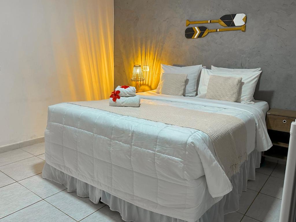 uma grande cama branca com um ursinho de peluche em Casa Flôr em Fernando de Noronha