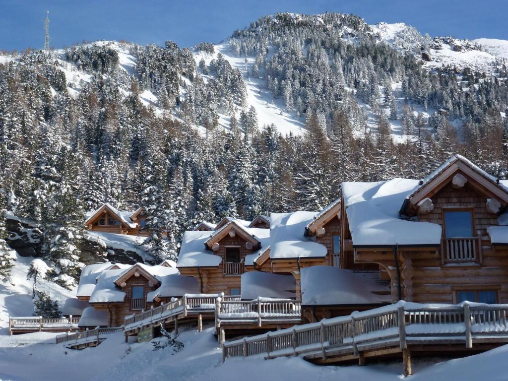 a lodge covered in snow with a mountain in the background at Mei Zeit Hüttendorf in Turracher Hohe