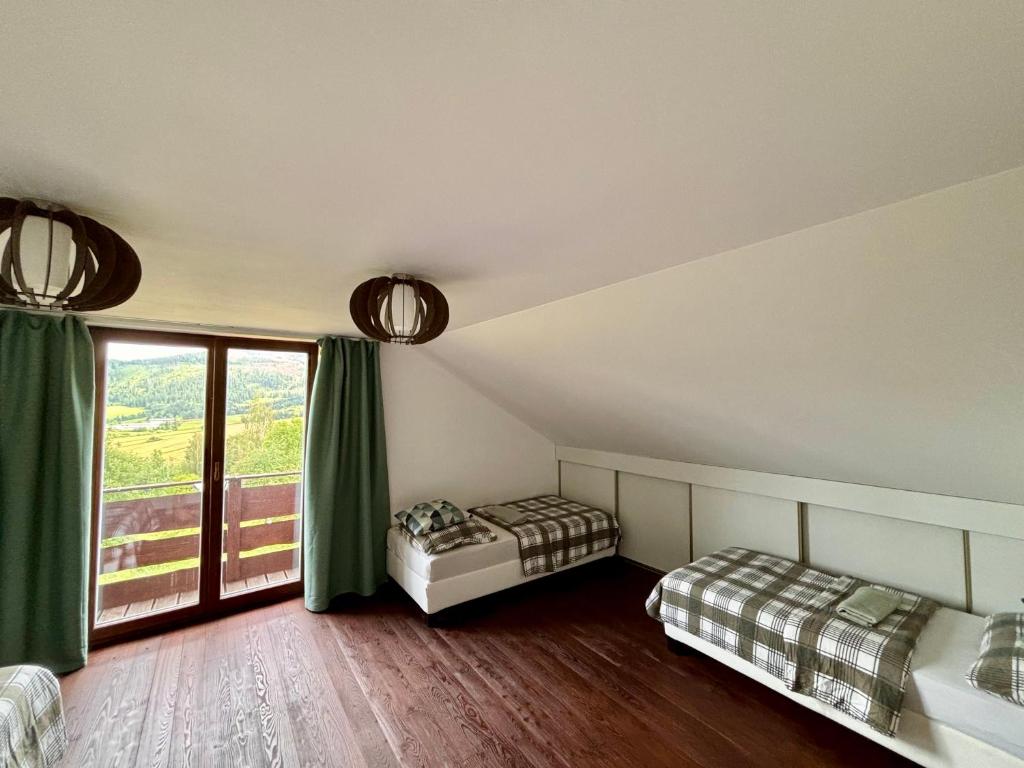 a bedroom with two beds and a large window at Chata pod Grúňom in Veľké Borové