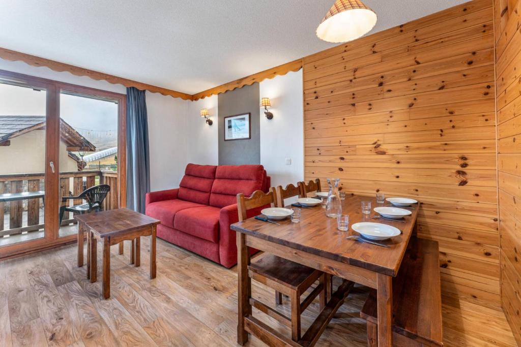 - une salle à manger avec une table et un canapé rouge dans l'établissement Résidence Les Hauts De Preclaux - Appartement au coeur des Orres 1800 MAE-7051, aux Orres