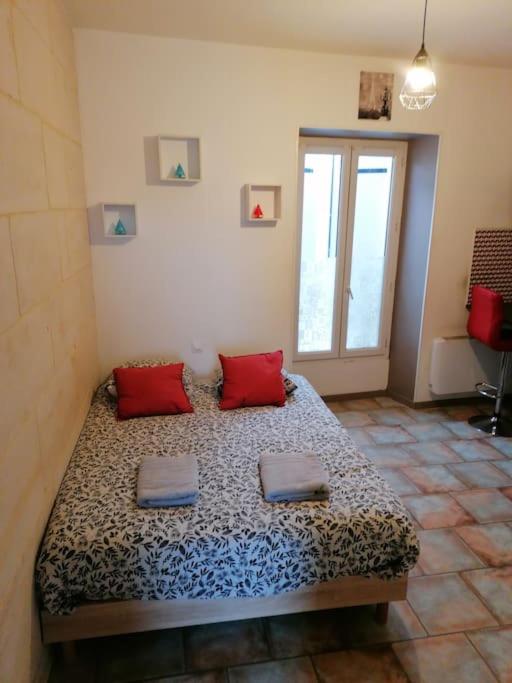 a bedroom with a bed with red pillows on it at Le Petit Cosy 2e étage 15 m2 in Niort