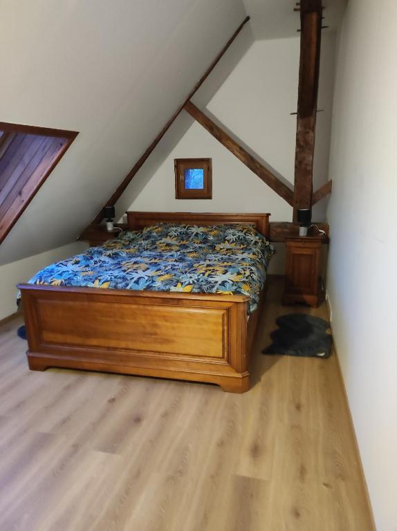 - une chambre mansardée avec un lit en bois dans l'établissement Le domaine de la remangerie, à Nogent-sur-Loir