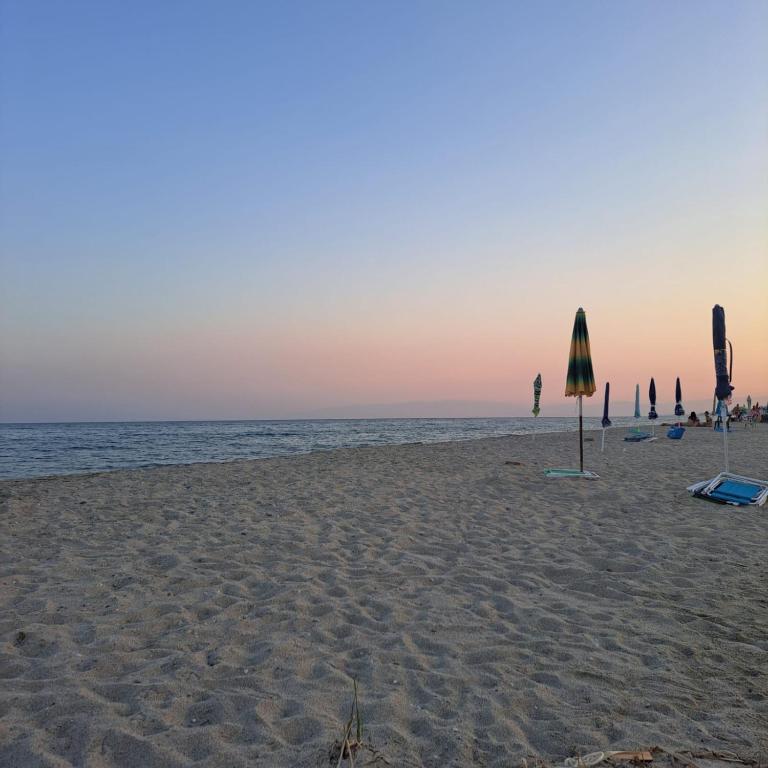 a beach with an umbrella and chairs and the ocean at La Terrazza sul Mare in Sellia Marina