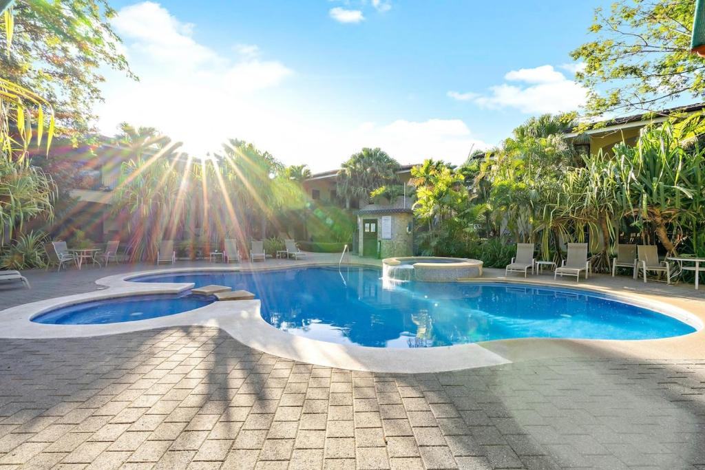 a swimming pool in a yard with chairs and the sun at Garden Pool & 5-minutes Walk to Beach in Potrero