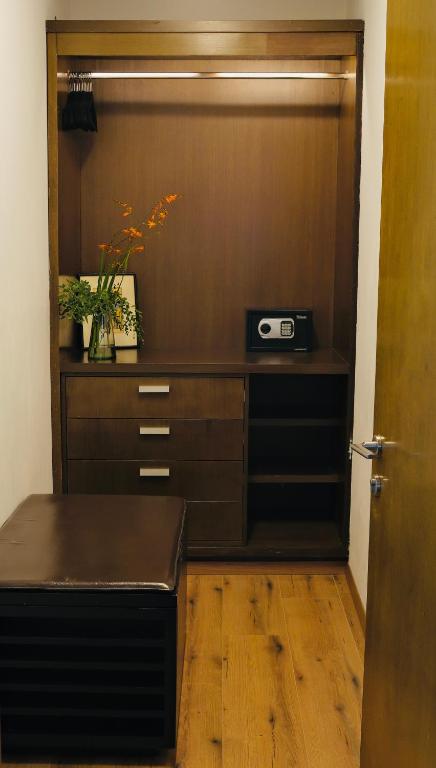 An open wooden wardrobe combines hanging space, drawers, a safe, and a compact desk surface.
