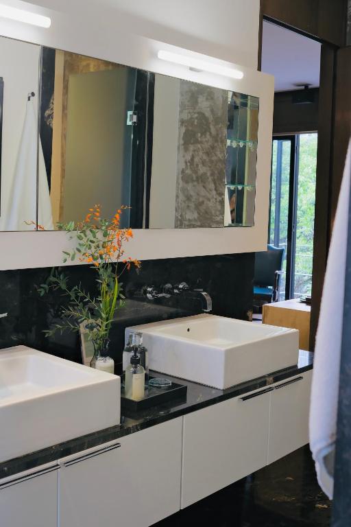 A contemporary bathroom vanity with two vessel sinks, a wide mirror and black stone surfaces.