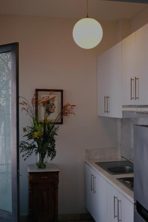 A compact kitchen corner with white cabinetry, a sink and a floral arrangement.