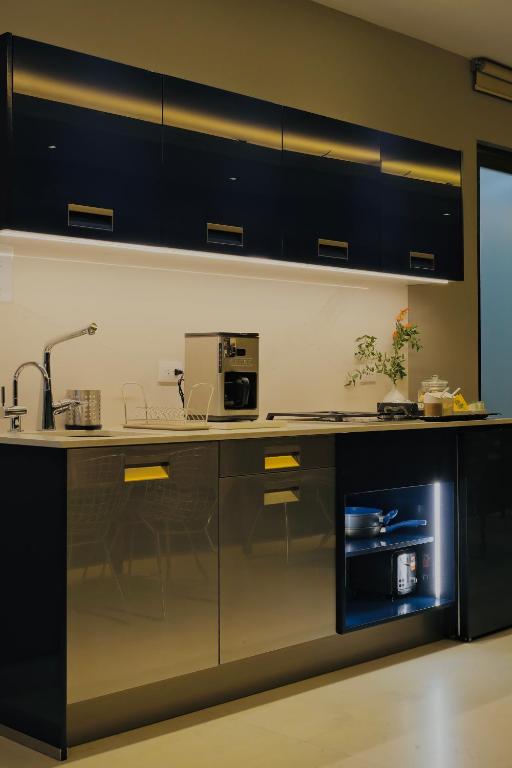 A compact black-and-metal kitchenette with coffee equipment and under-counter storage.