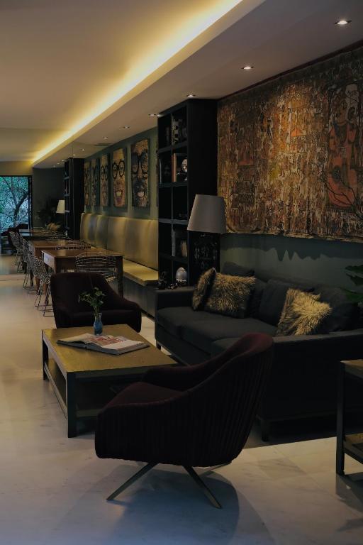 A richly decorated lounge with sofas, armchairs, bookshelves and large artworks.