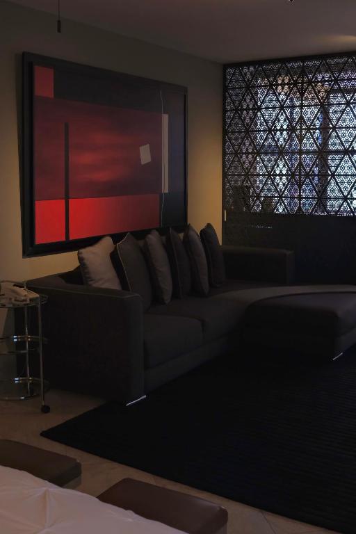 A dark upholstered sofa area beside a patterned window, with bold red abstract wall art.