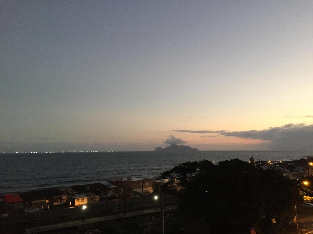 a view of the ocean at sunset with an island in the distance at Dali Yi International Hostel in Toucheng