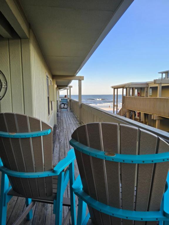 two chairs sitting on a deck next to the beach at Living the Dream 2 Bedroom Ocean View Cozy Condo in Gulf Shores