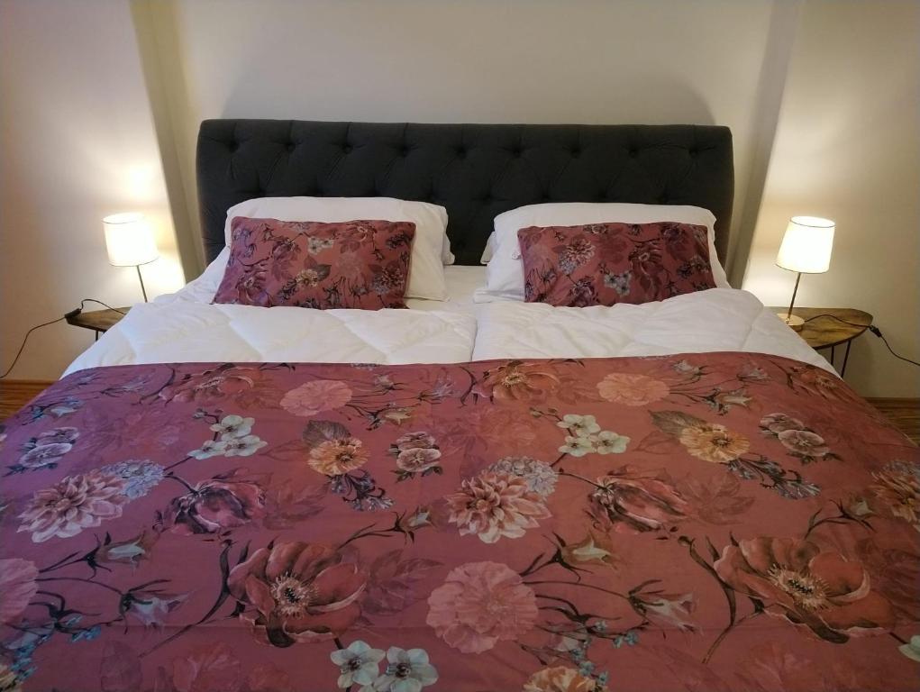 a large bed with a floral bedspread and two pillows at Luxusní byt v centru - Free Parking in Karlovy Vary