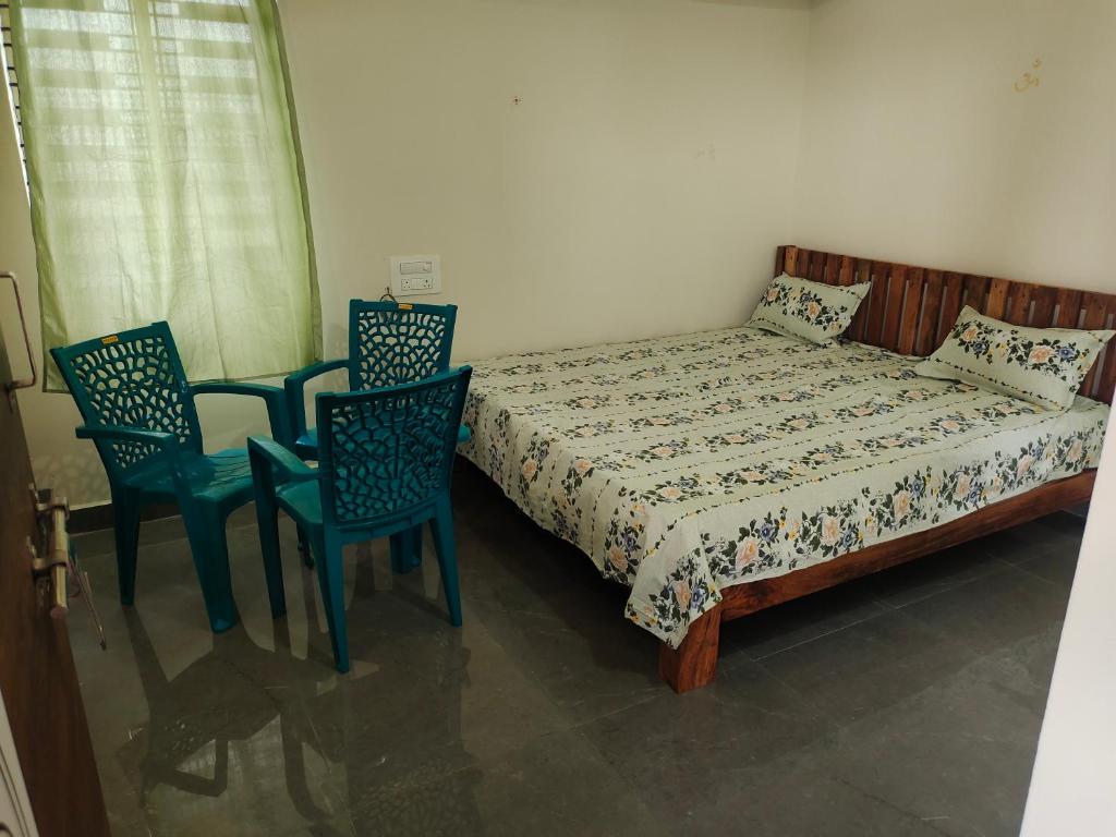 a bedroom with a bed and two chairs at SHIVADIVYA Homestay Hampi in Hampi