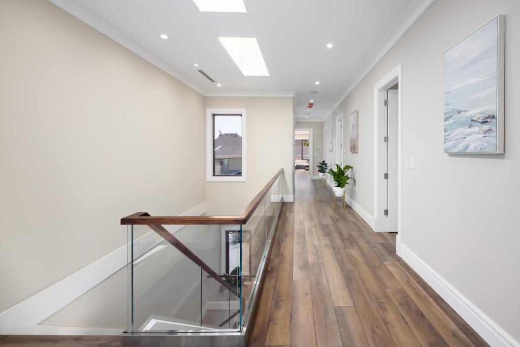 a hallway with white walls and a staircase with wood floors at Vancouver Vacation Home in Richmond