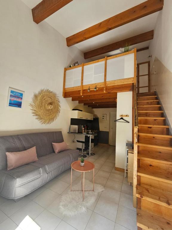 Una sala de estar con un sofá y una escalera. en Gîte Lo Becarut L'Escapade Des Flamants Roses, en Mireval
