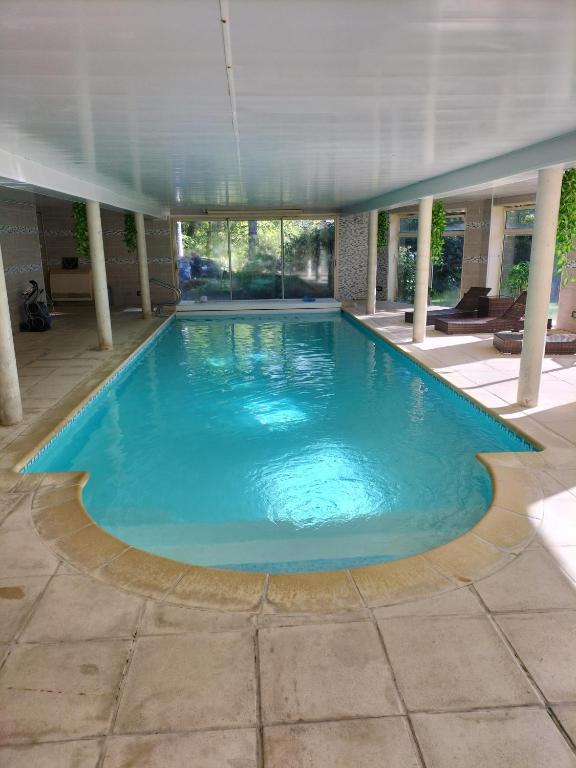 弗尔黎祖Au Charme du Lac Espace bien être et Piscine chauffé proche parc et restaurant du casino的建筑物内有蓝色水的大型游泳池