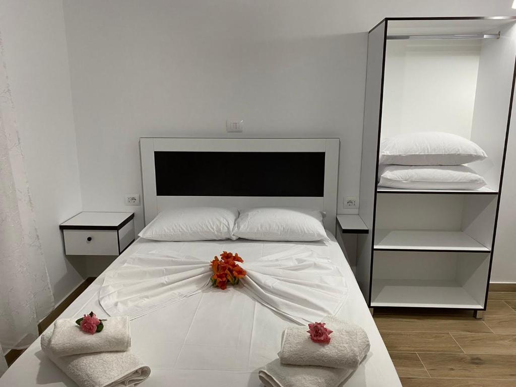 a white bed with red flowers on top of it at Rentrooms Geni in Ksamil