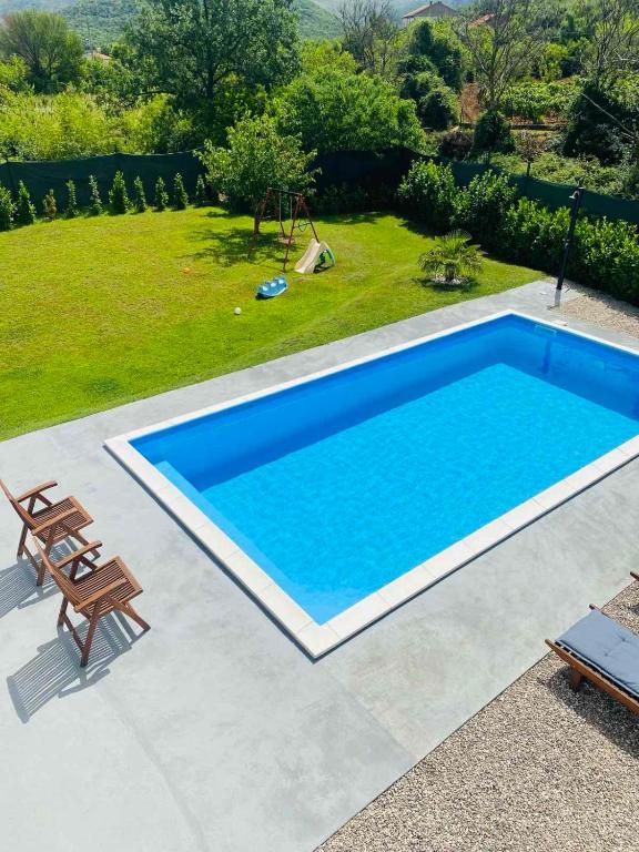 a large blue swimming pool next to a yard at Holiday House Maya in Mostar