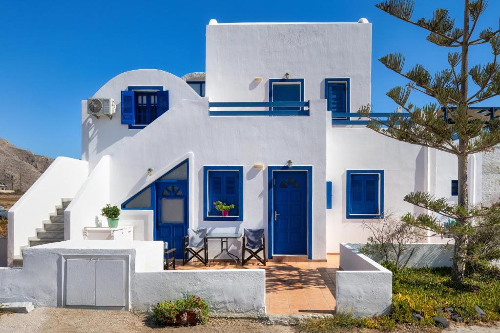 a white house with blue doors and a tree at Georgia's Comfort Studio in Perivolos