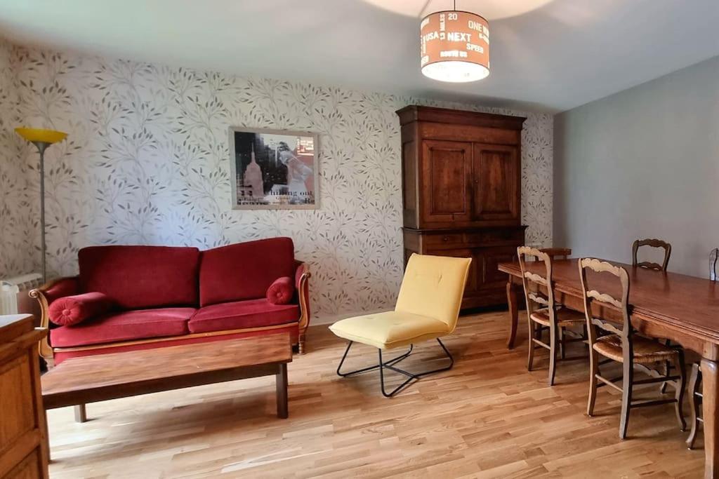 un salon avec un canapé rouge et une table dans l'établissement Bel Appartement et Jardin hyper Centre de Dol, à Dol-de-Bretagne