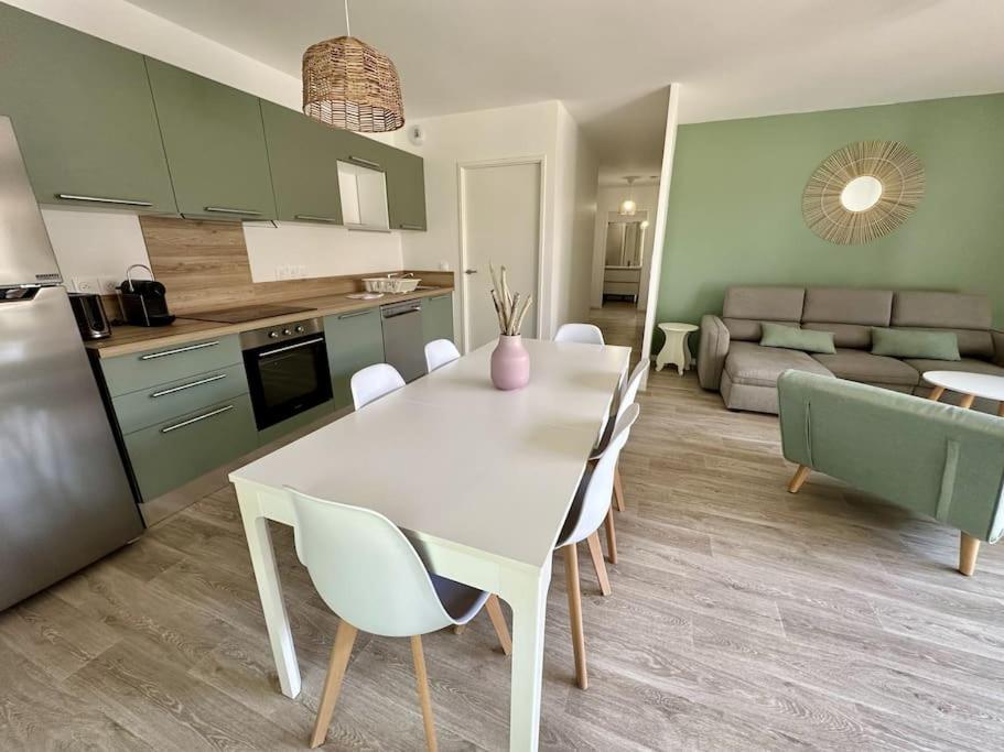 une cuisine et un salon avec une table et des chaises blanches dans l'établissement spacieux T3 calme et lumineux, à Carcans