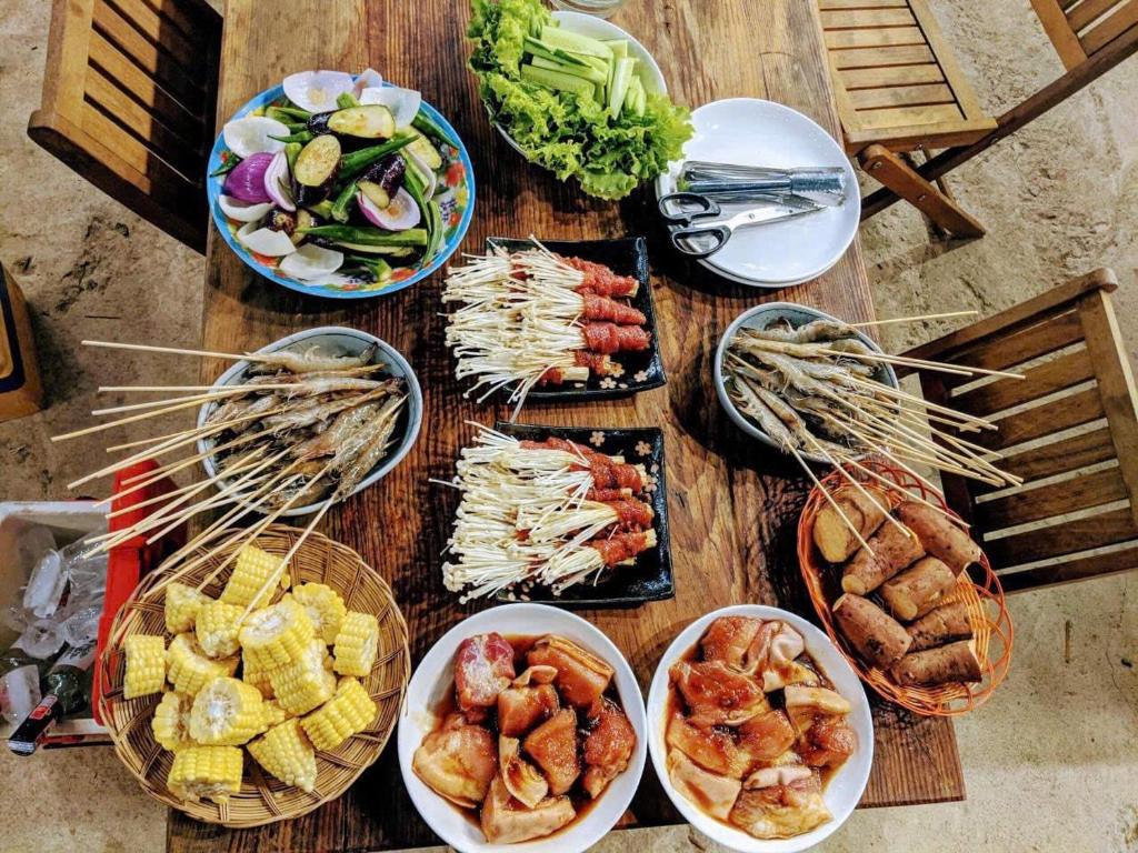 una mesa de madera con platos de comida y tazones de comida en Tomorrow Homestay Đà Lạt, en Da Lat