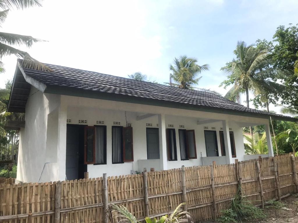 a small white house with a wooden fence at Homestay Saptia Dewi in Sengkol