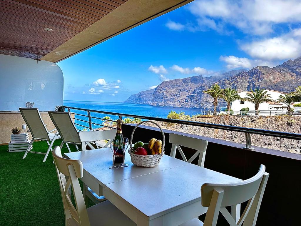 a table with a basket of fruit and a view of the ocean at Cliffside Residence in Puerto de Santiago