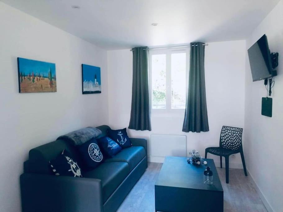 a living room with a blue couch and a table at Le Chêne pommier Marine in Fatouville-Grestain