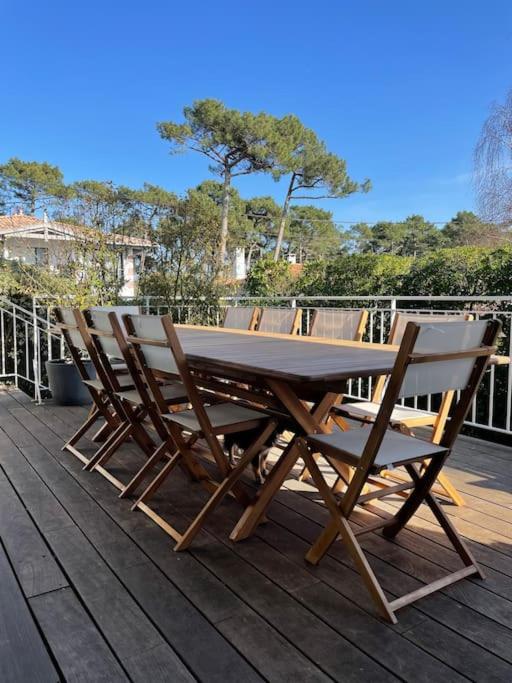 une table et des chaises en bois assises sur une terrasse dans l'établissement Villa Faustine Arcachon, à La Teste-de-Buch