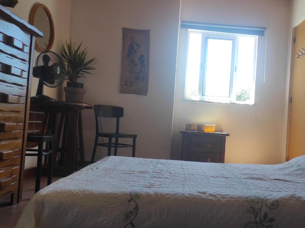 a bedroom with a bed and a window and a table at Casa da Cabana in Budens