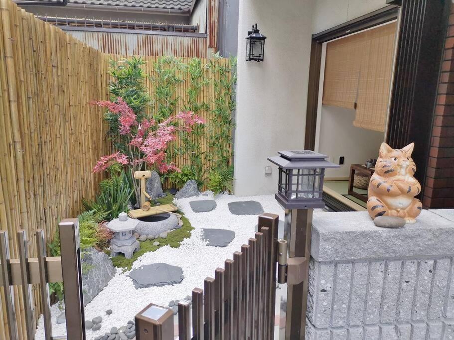a garden with a cat statue sitting on a fence at House[80㎡]/Direct to Numba 7 min ~楽雅苑 Rakugaen~ in Osaka