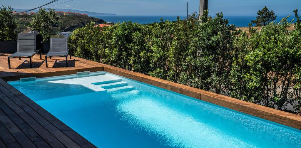 a swimming pool with two chairs next to at Ocean View Pool Villa Family & Surf in Ericeira in Ribamar