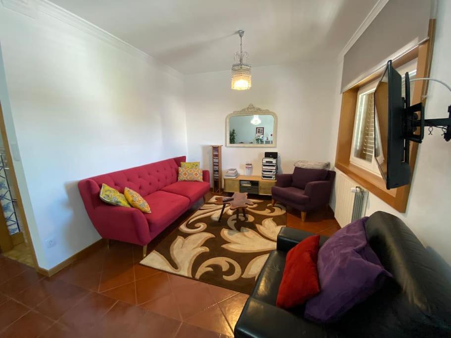 a living room with a red couch and a mirror at Casa Eva e Eduardo in Macedo de Cavaleiros