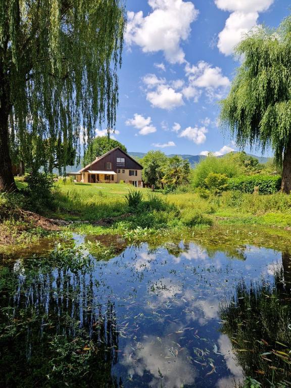 a house and a pond in front of a house at Le Temps d'une Pause in Andert-et-Condon