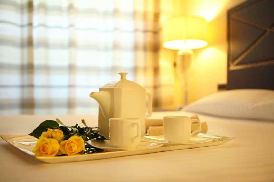 a tea set on a tray with two cups and roses at Hotel Cristallo in Giulianova