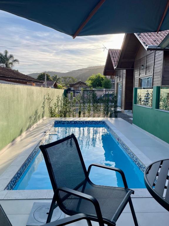 a chair sitting next to a swimming pool at Chalés Costa Esmeralda Com Piscina , Bombinhas in Bombinhas