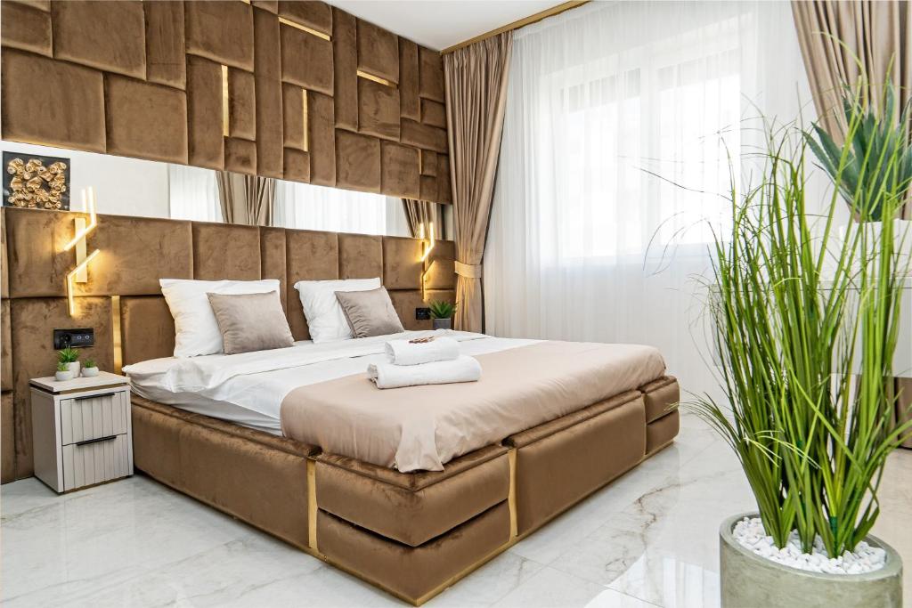 a bedroom with a large bed and two potted plants at Fashion Stay - Valentino Home - By OpenHouse in Giroc