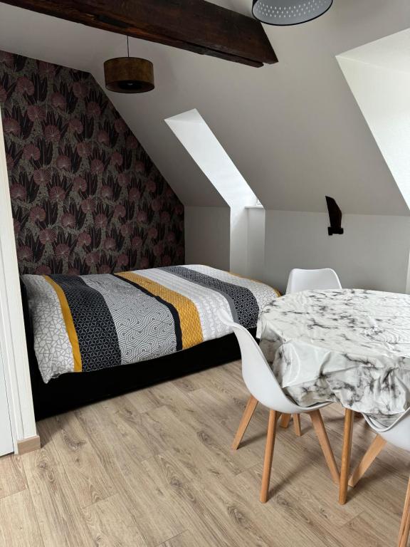 a bedroom with a bed and a table and chairs at Studio 3ème étage - Centre-ville - Local vélos disponible in Mayenne