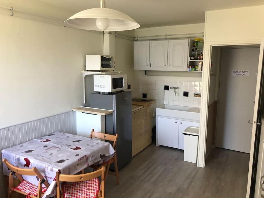 a kitchen with a table and a kitchen with white cabinets at Duplex Praloup in Uvernet-Fours