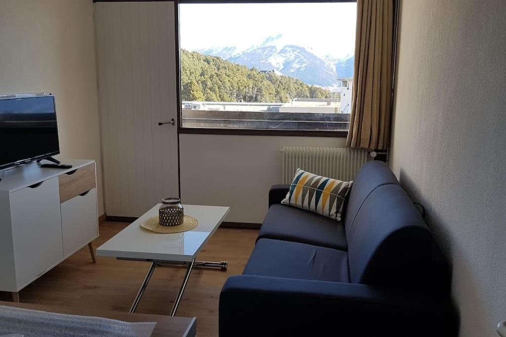 un salon avec un canapé bleu et une grande fenêtre dans l'établissement Egat font-romeu Appartement 2ème étage, à Égat