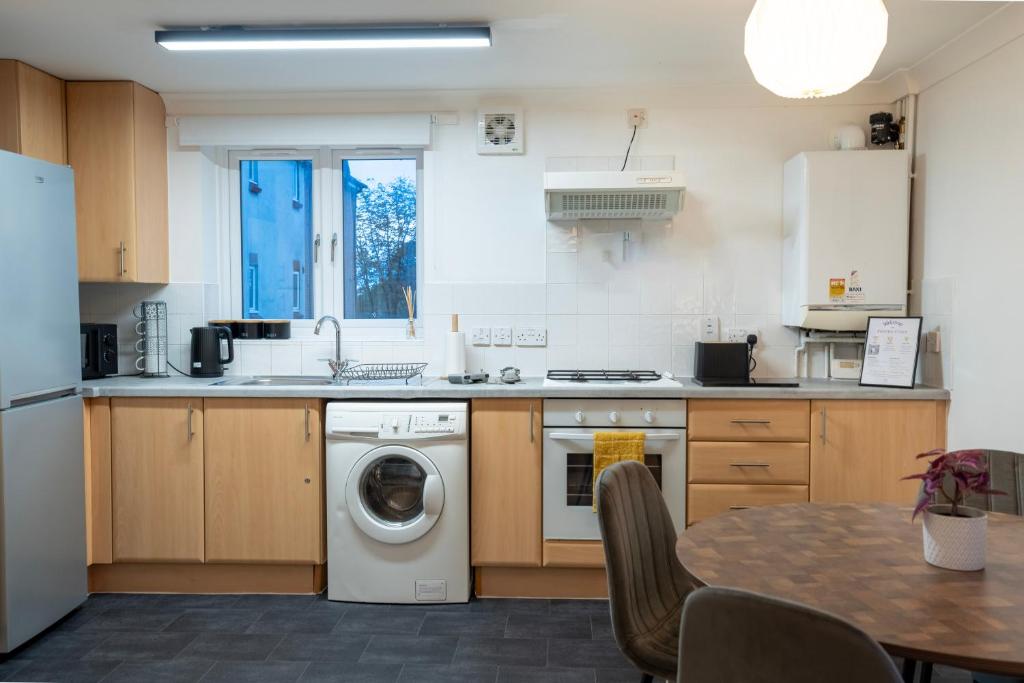 eine Küche mit einer Waschmaschine und einem Tisch in der Unterkunft Beautiful 2-Bed City Centre Apartment with Balcony in Milton Keynes