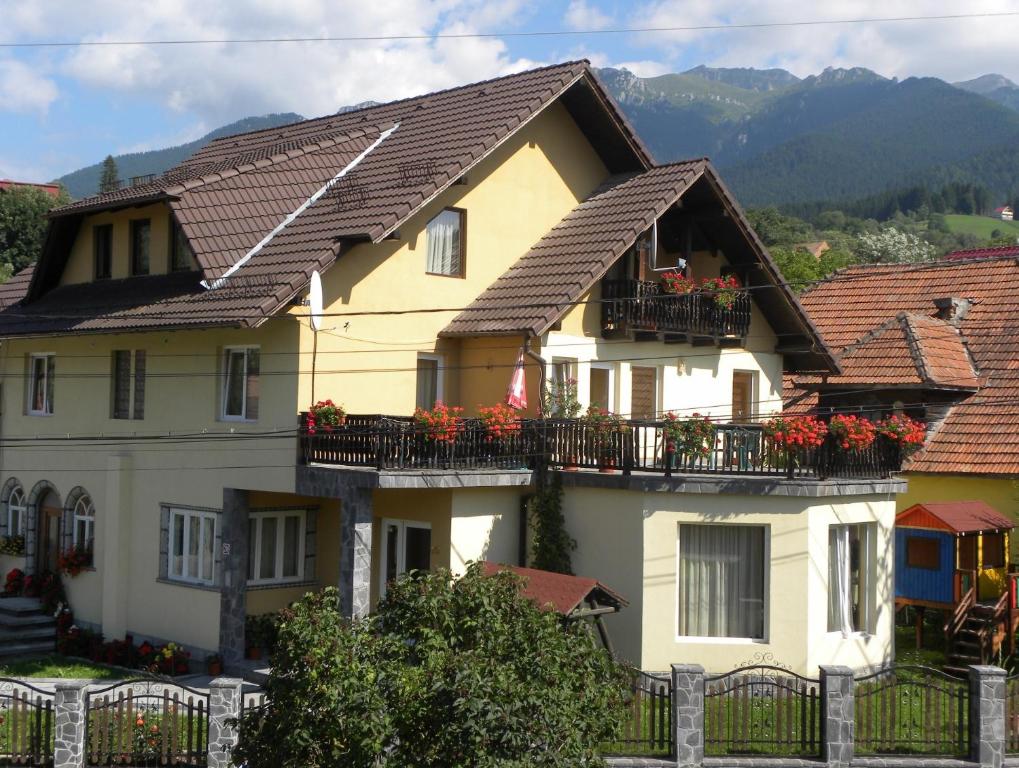 une maison jaune avec des fleurs sur les balcons dans l'établissement Casa Enescu, à Bran