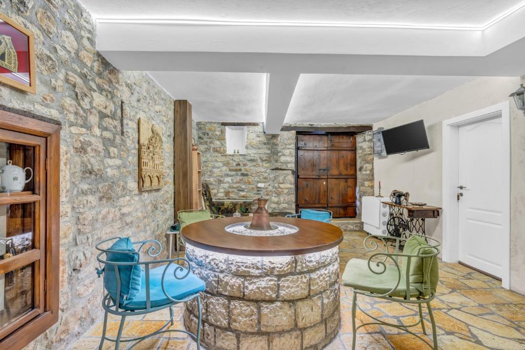 a room with a stone wall and a table and chairs at The Well House - UNESCO in Berat
