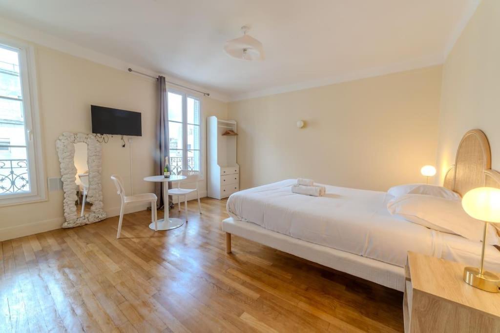 une chambre avec un lit, une table et une télévision dans l'établissement La Suite Victor Hugo, à Paris
