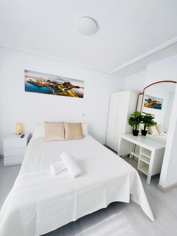 a white bedroom with a white bed and a mirror at Apartamento en Santander in Santander