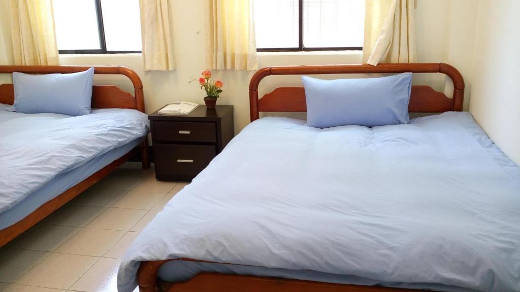 花蓮市にあるLove Hualien Hostelのベッドルーム1室(青い枕のベッド2台付)