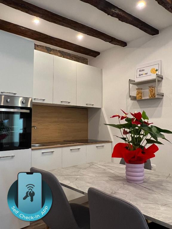 a kitchen with white cabinets and a table with a vase of flowers at Casa Salvia in Koper